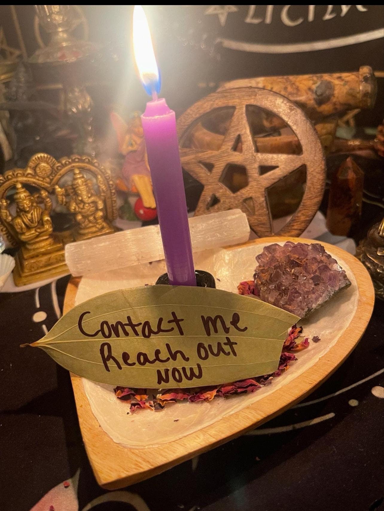 May include: A wooden heart-shaped dish with a purple amethyst crystal, dried rose petals, and a bay leaf with the handwritten message 'Contact me reach out now'.
